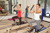 Two women exercising on pilates reformers